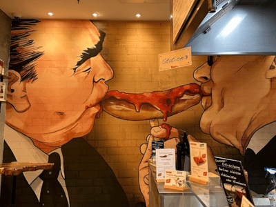 A humorous mural of two characters sharing a plate of currywurst at Curry 61, illustrating the friendly atmosphere.