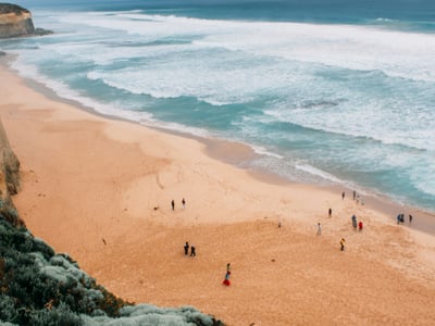 Princetown Beach, with people enjoying the waves and golden sand under a cloudy sky. Awakening of coastal nature.