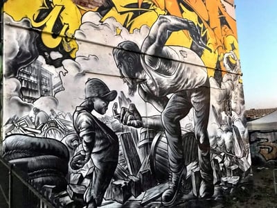 Murale saisissant sur le RAW-Gelände, représentant un homme intimidant un enfant, symbolisant la lutte et la résilience urbaine.