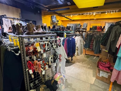 Magasin vintage Beyond Retro Soho, présentant une variété de vêtements, chaussures et accessoires colorés sur des présentoirs.