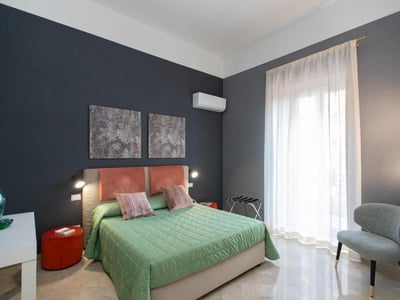 Modern room at Garruba house 2, with a double bed, dark wall, and natural light through large windows.