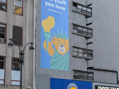 Bear holding a torch in front of the Build-A-Bear Workshop building, illustrating the creative spirit in New York.