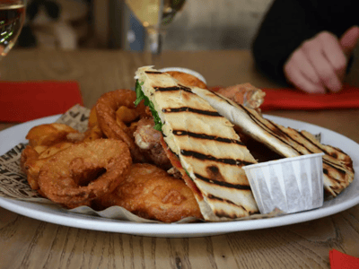 Delicious grilled sandwich with salad, accompanied by crispy onion rings, served at The Anchor.