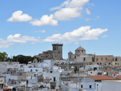 Panoramic view of Ceglie Messapica, showcasing the historical buildings and the medieval tower under a blue sky.