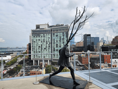 Sculpture of a man running with branches on his head, seen from the terrace of the Whitney Museum of American Art.