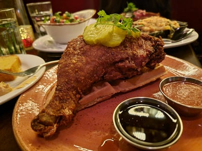Crispy fried chicken served on a waffle, accompanied by pickles and sauces, at Red Rooster in Harlem.