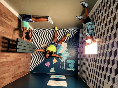 Trois personnes s'amusent dans une salle d'illusions du Musée des illusions, créant des effets visuels surprenants.