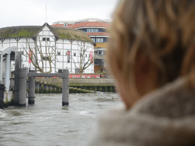 View from Westminster Pier, with a traditional building and a person looking at the river. Peaceful atmosphere in the city.