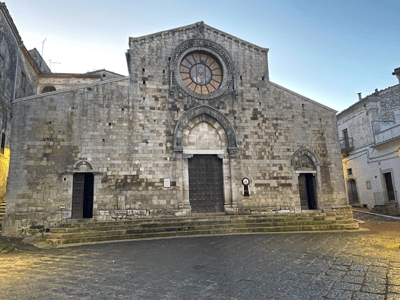 Stone façade of the Cathedral of Bovino, revealing medieval architectural details under a clear sky.