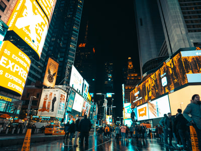 L'animation nocturne à Times Square, avec ses panneaux lumineux et la foule se mêlant sur la route mouillée.
