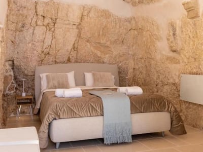 Modern room with natural stone wall at Cà sotto l’arco, combining comfort and historical charm.