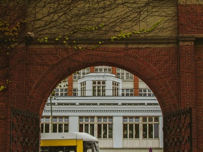 Arched view at Hackescher Markt, with a yellow tram line and a historic building in the background.