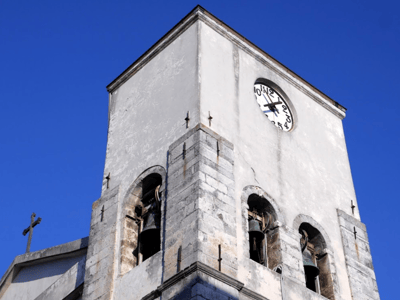 Tour du clocher de la Collegiata dell'Assunta, avec ses cloches et une belle horloge sur fond de ciel bleu.
