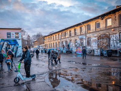 Ambiance vivante au RAW-Gelände, avec des visiteurs se déplaçant entre des bâtiments recouverts de graffitis.
