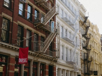 Bâtiments historiques à Soho, avec des escaliers de secours et une boutique DIESEL en devanture, évoquant le style urbain new-yorkais.