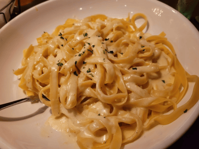 Creamy fettuccine with Alfredo sauce, topped with parsley, typical of Olive Garden dishes.