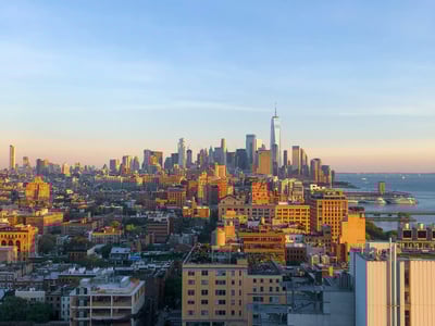 Panoramic view of Chelsea with the Manhattan skyline and the One World Trade Center under a clear sky at sunset.