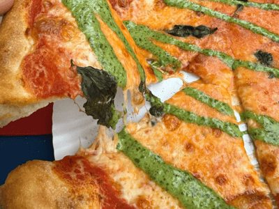 Pizza garnie de pesto et de basilic, servie au Salami Social Club, mettant en valeur une délicieuse cuisine italienne.