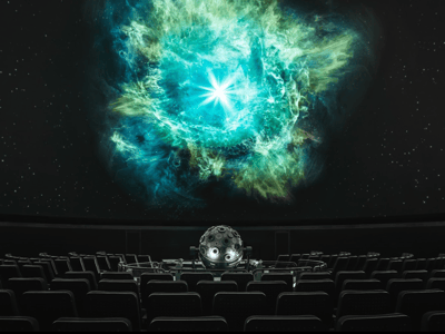 Projection of the cosmos at the Zeiss planetarium, with empty seats and a bright star in the center of the screen.