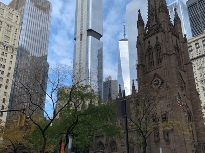 Église historique au cœur du Financial District, entourée de gratte-ciel modernes et d'une végétation printanière.