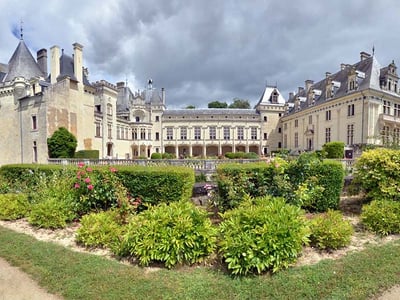 Château de Brézé, avec ses jardins bien entretenus et son architecture historique sous un ciel nuageux.
