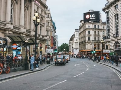 A lively corner of Trafalgar Square, with pedestrians, taxis, and iconic buildings in the background.