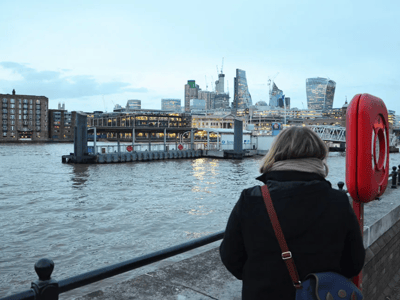 View from Westminster Pier with boats and the modern silhouette of London in the background at dusk.