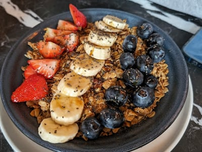Bol de granola coloré avec fraises, bananes et myrtilles, servi à Music & Beans pour un petit-déjeuner sain.