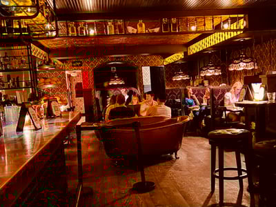 Warm atmosphere at Bathtub Gin, with relaxed customers and a wooden bar, vintage decor, and subdued lighting.