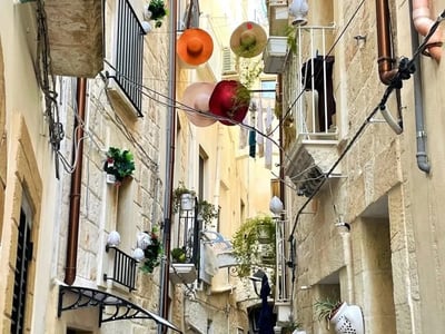 Ruelle colorée à Monopoli, ornée de chapeaux suspendus et de plantes, reflétant l'architecture méditerranéenne.