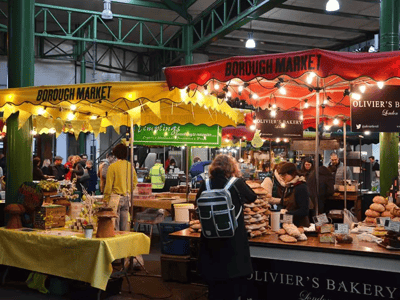 Colorful and lively stalls of Borough Market, with visitors admiring artisanal products and baked goods.