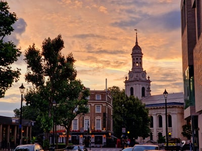 Coucher de soleil sur Greenwich, mettant en valeur l'architecture historique et l'église emblématique en arrière-plan.