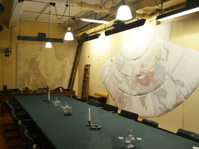 Salle de stratégie des Churchill War Rooms avec une grande table et des cartes historiques sur les murs. Atmosphère d'époque.