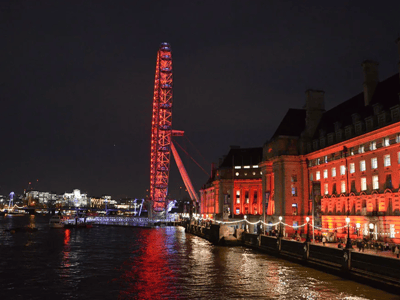 The London Eye lit up in red, overlooking the Westminster pier by the Thames.