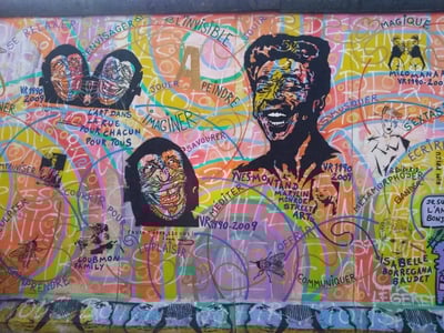 Mur coloré de l'East Side Gallery présentant des portraits expressifs et des messages artistiques sur la vie et l'imagination.