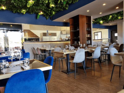 Salle à manger élégante de Ricci Braceria, décorée de plantes vertes, prête à accueillir des clients pour un repas convivial.