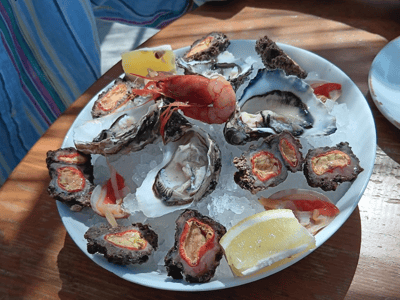 Plate of fresh seafood with oysters and a shellfish, enjoyed at Al Trabucco da Mimì by the seaside.