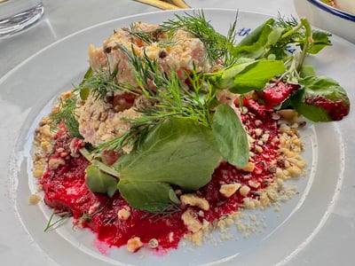 Salade colorée avec des morceaux de poisson, herbes fraîches, et coulis de betterave, servie au restaurant The 10 Cases.