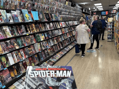 Client dans Midtown Comics explorant des bandes dessinées Spider-Man, entouré de nombreux étagères de comics colorés.