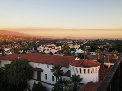 Vue panoramique de Santa Barbara au coucher de soleil, montrant des maisons et des montagnes en arrière-plan.