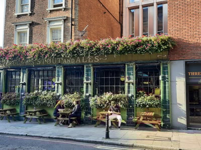 Lively terrace of a pub at Three Crown, decorated with colorful flowers, with customers enjoying drinks outdoors.