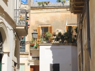 Une ruelle pittoresque à Lecce, montrant des balcons fleuris et une ambiance méditerranéenne accueillante.