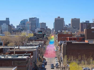 Vue panoramique de Le Village, avec des rues colorées et un skyline moderne en arrière-plan, célébrant la diversité.
