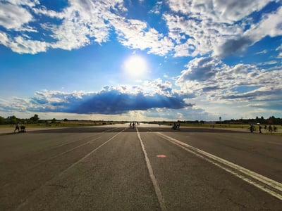 Clear blue sky above Tempelhof, with clouds, people enjoying the open space on an old runway.