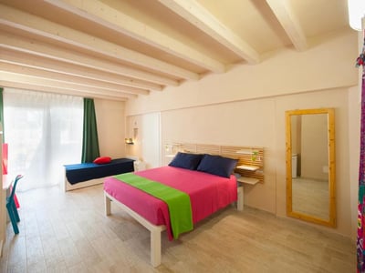 Chambre colorée à Villa Bruno avec un lit vibrant et un sofa, idéale pour un séjour relaxant.