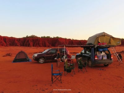 Camping at James Prices Point, with cars and tents on red sand at sunset, creating a peaceful atmosphere.