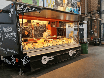 Artisanal cheese stand at Markhalle Neun, offering a variety of local cheeses in a friendly atmosphere.