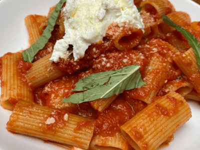 Rigatoni pasta covered in tomato sauce and ricotta, topped with fresh basil, served at Adrienne's Pizzabar.