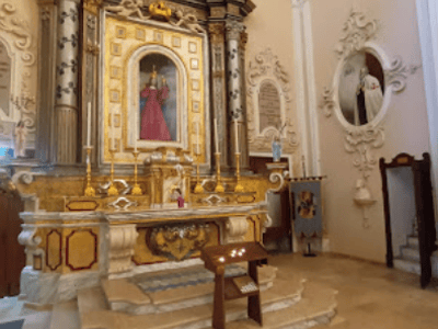 Baroque altar of the Church of San Domenico, decorated with gilding and a representation of the saint, in a beautifully lit interior.