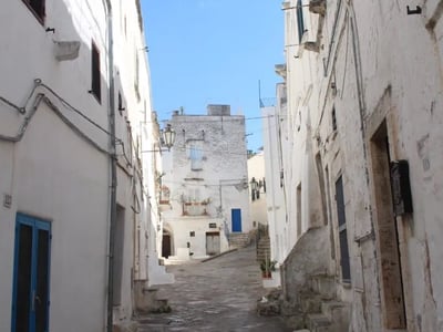 Paved street of Ostuni, flanked by white houses, highlighting the picturesque architecture and Mediterranean atmosphere.